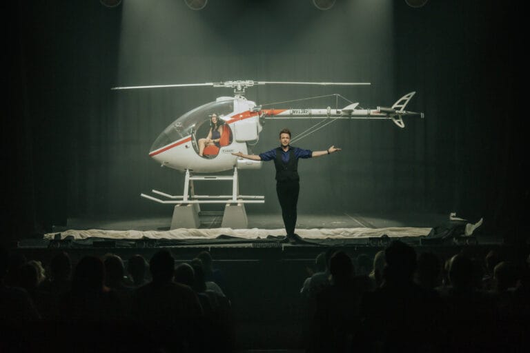 Ein Hubschrauber steht auf der Bühne, davor Florian Zimmer mit ausgebreiteten Armen